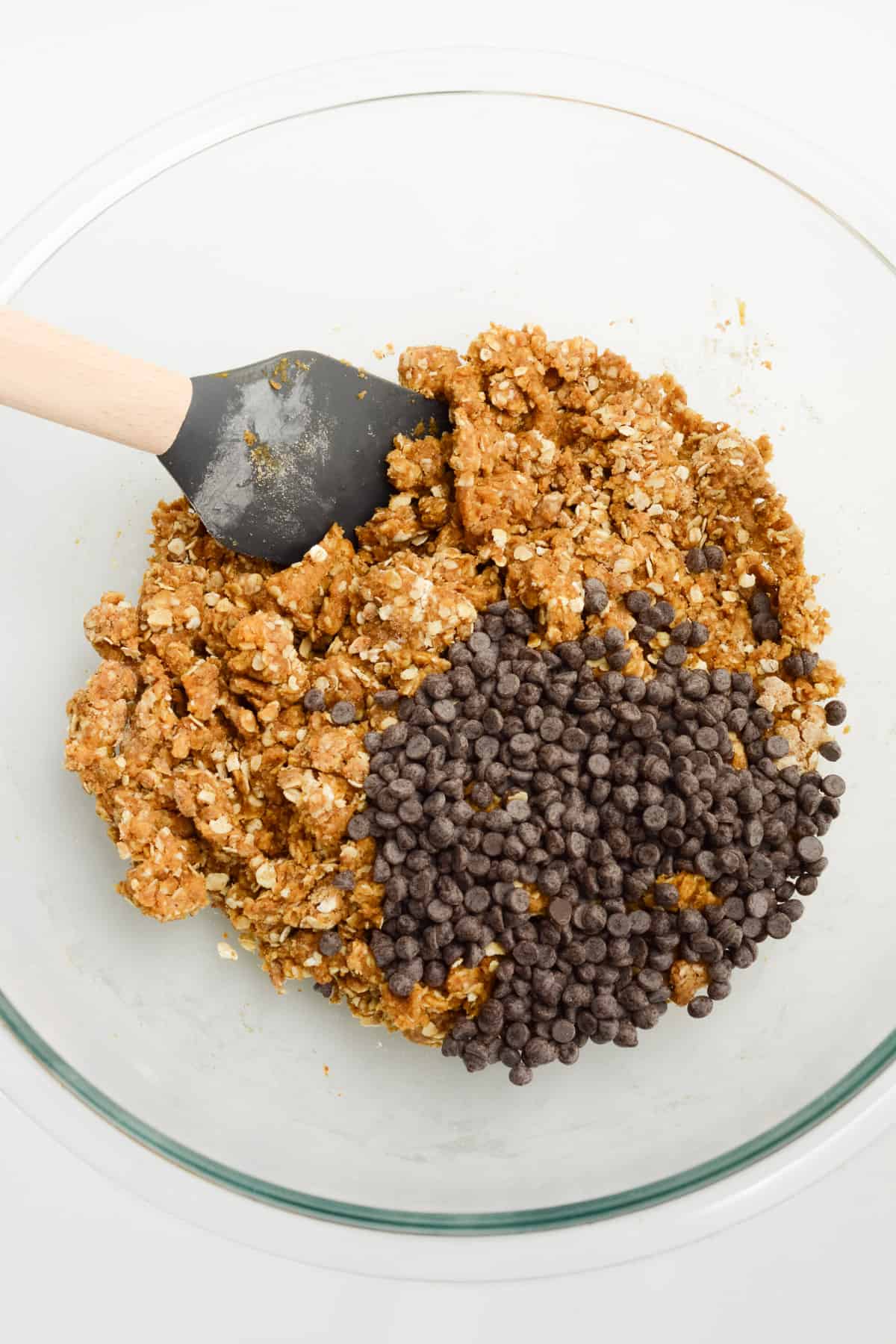 Chocolate chips added to a bowl of vegan oatmeal cookie dough.