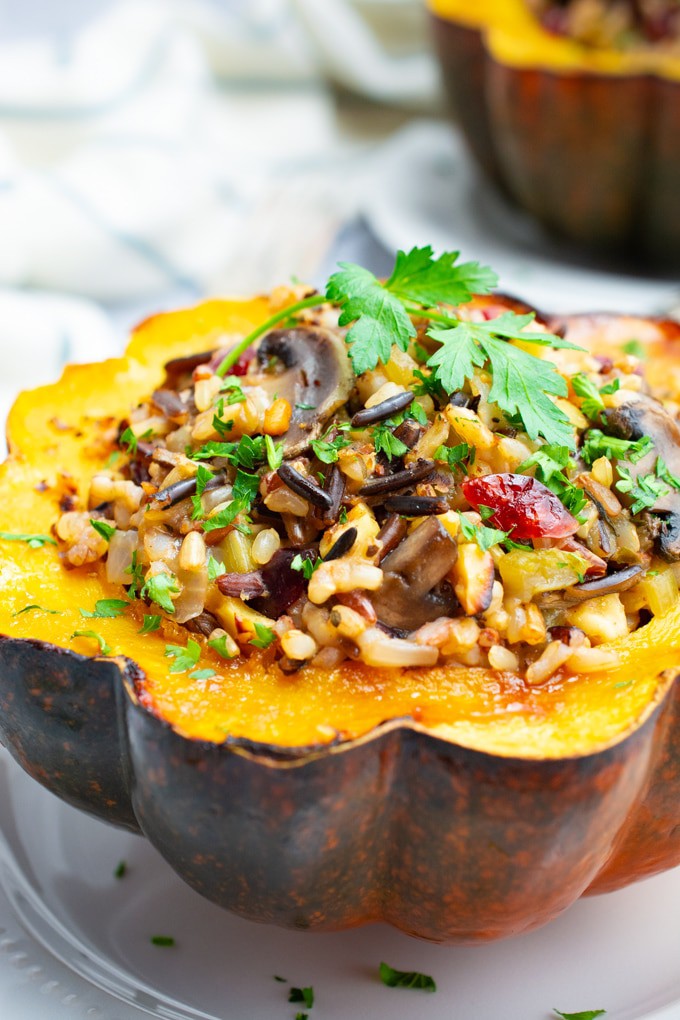 Vegan wild rice stuffed acorn squash topped with a fresh parsley leaf.