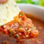 Homemade salsa scooped onto a tortilla chip.