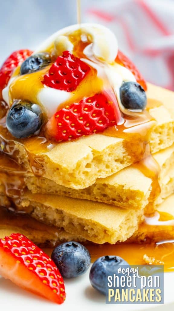 Sheet pan pancakes topped with fruit, whip and maple syrup.