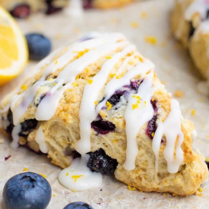 Blueberry scone with icing on parchement paper.