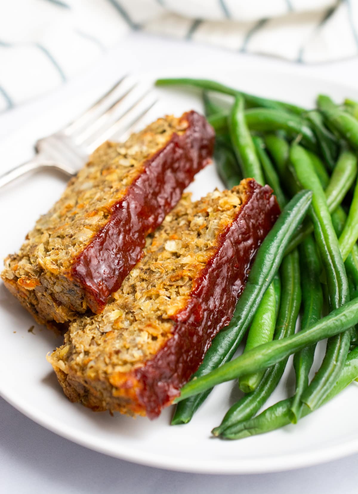 2 slices of lentil loaf topped with ketchup glaze and served with green beans.