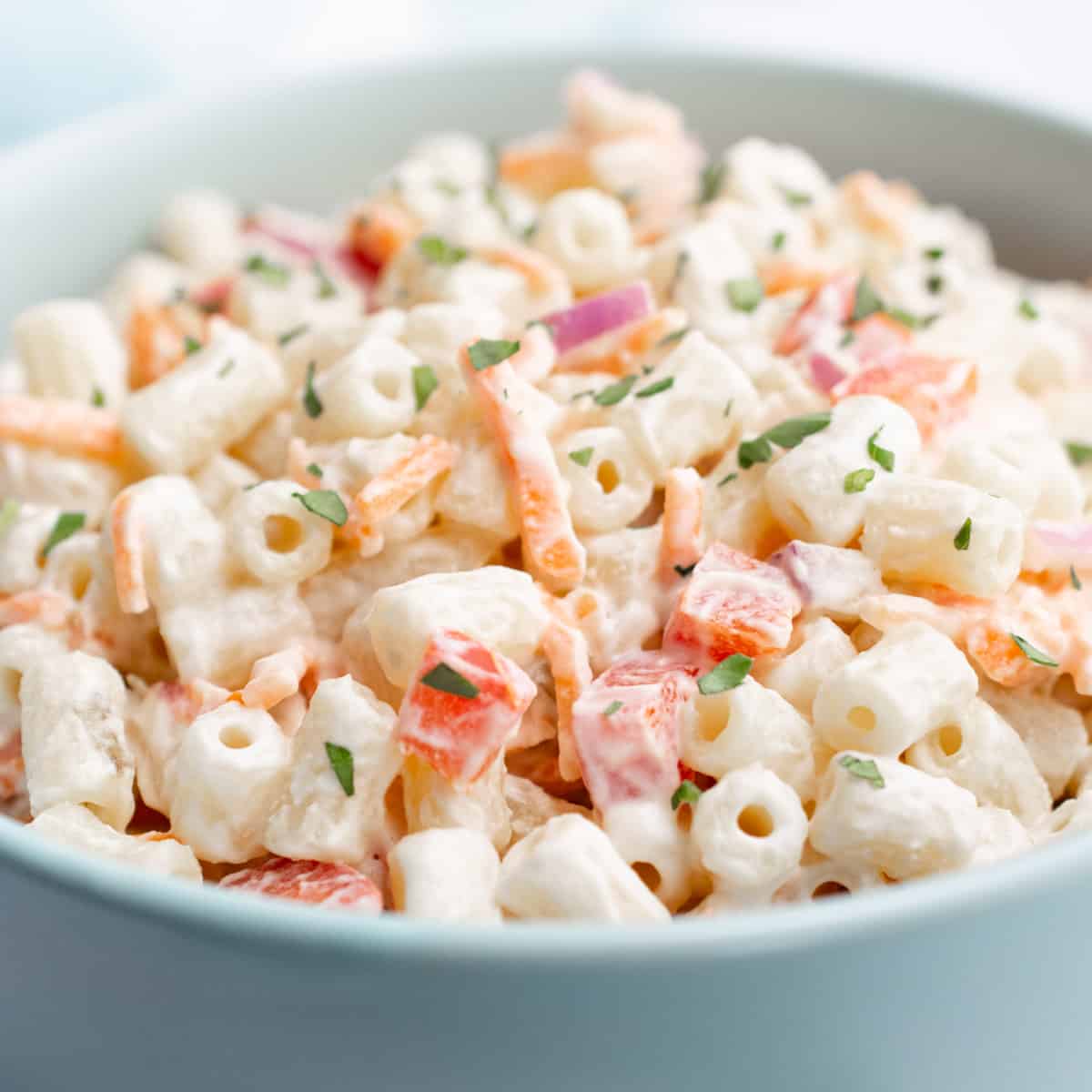 A turquoise bowl with vegan macaroni salad.