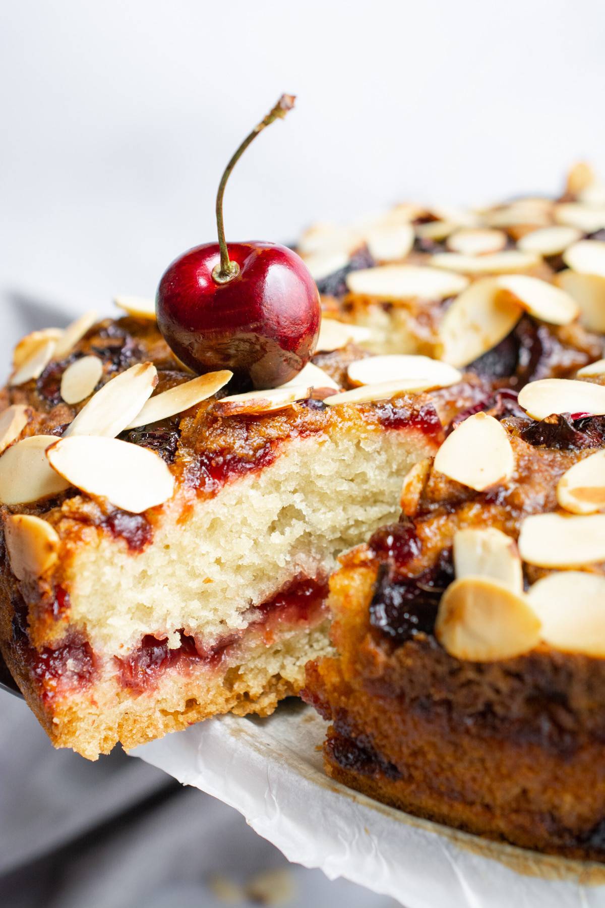 A slice of vegan cherry coffee cake being removed from the cake.