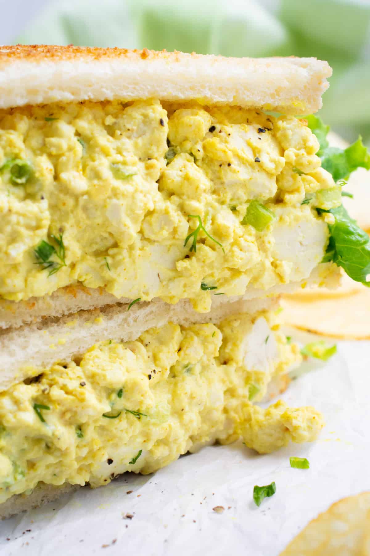 Vegan egg salad sandwich cut in half and stacked.