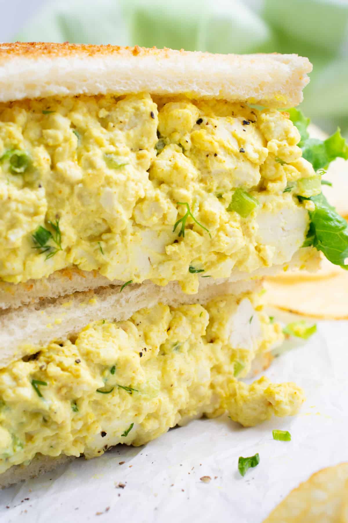 Vegan egg salad sandwich cut in half and stacked.