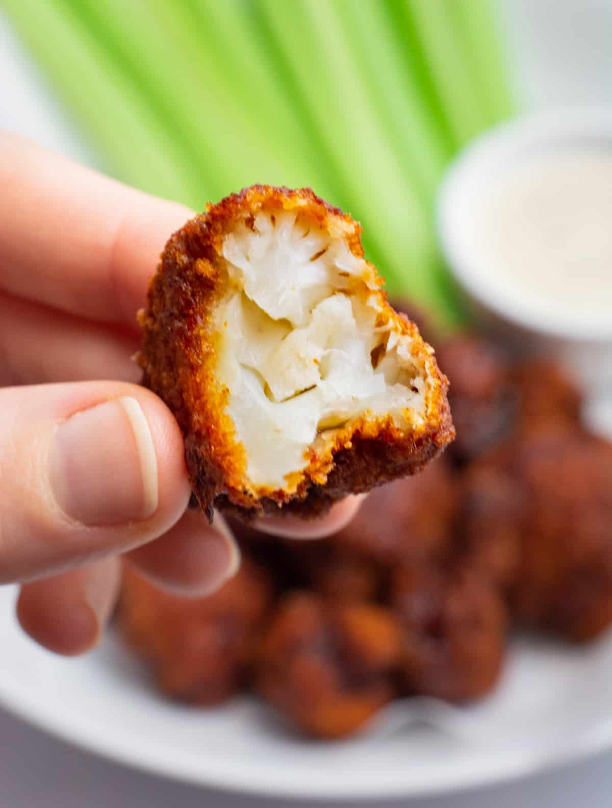 BBQ cauliflower wings with a bite taken out showing the inside.