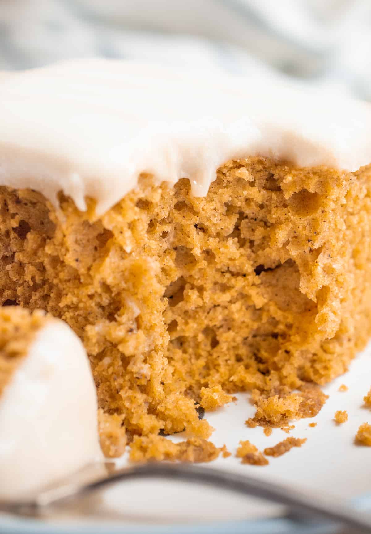 A slice of vegan pumpkin cake with a bite removed.