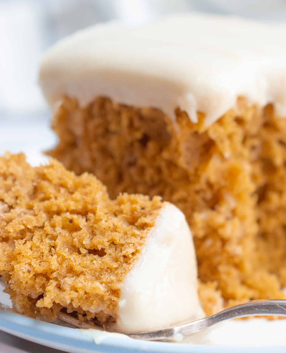 A bite of vegan pumpkin cake with frosting on a fork.