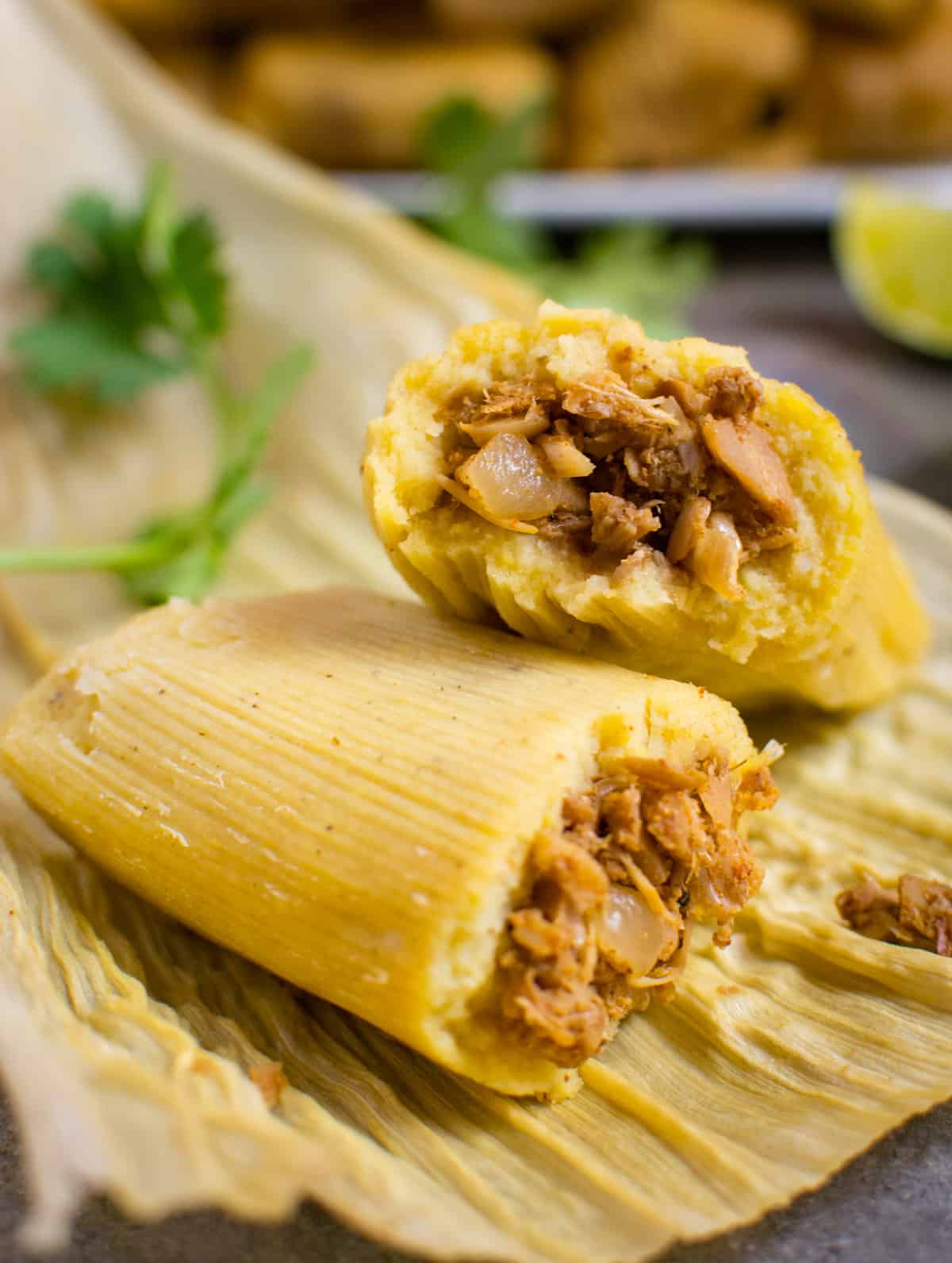 Jackfruit vegan tamale broken in half on a corn husk.