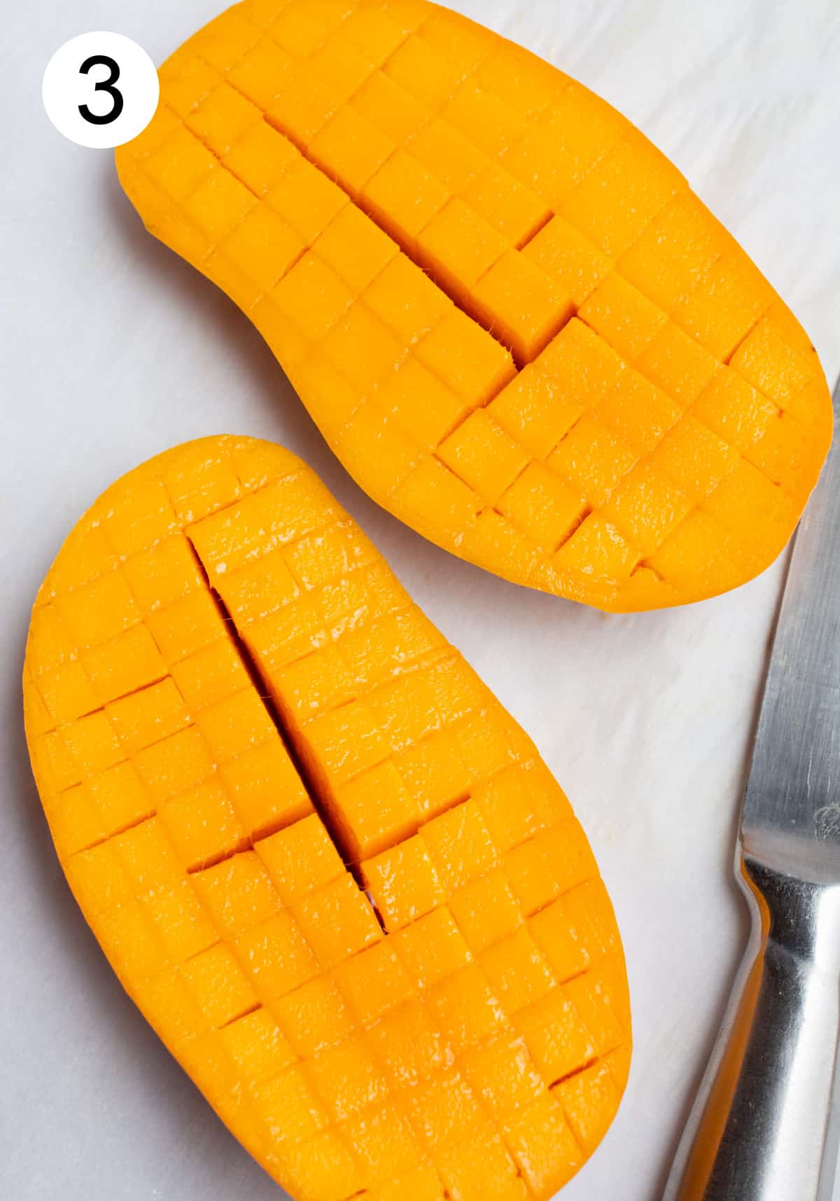 Two mango halves sliced into cubes in their skin.