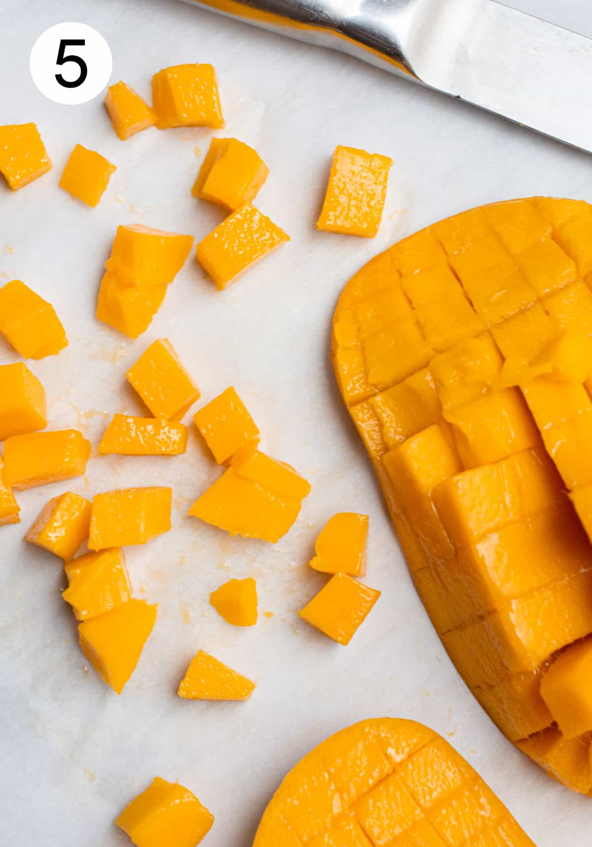 Cubes cut off of the mango skin laying on parchment paper.