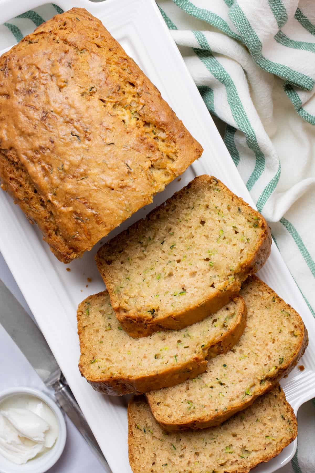 A loaf of vegan zucchini bread with 4 slices cut.