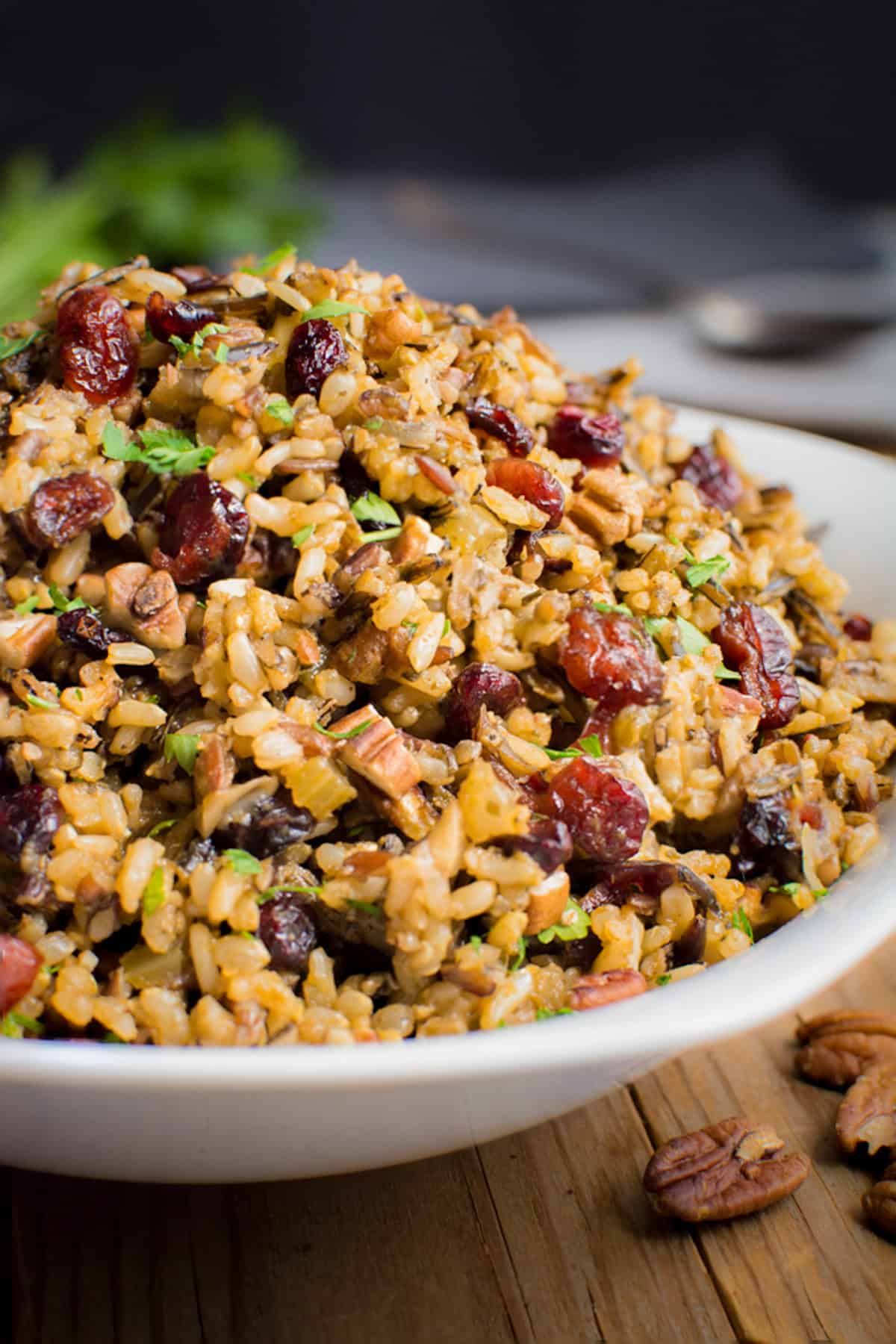 A serving bowl filled with wild rice stuffing with dried cranberries and toasted pecans.