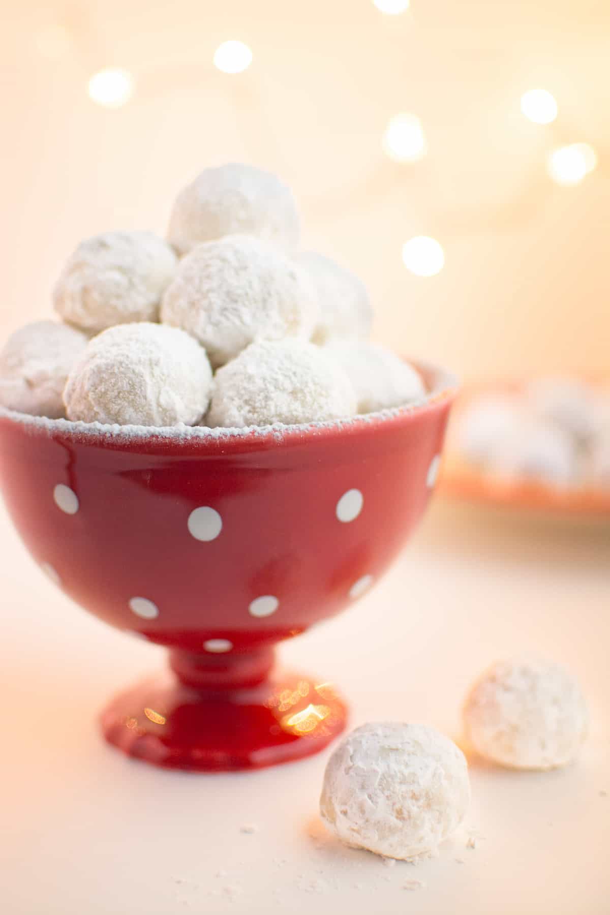 Vegan snowball cookies in a red holiday dish with white dots.