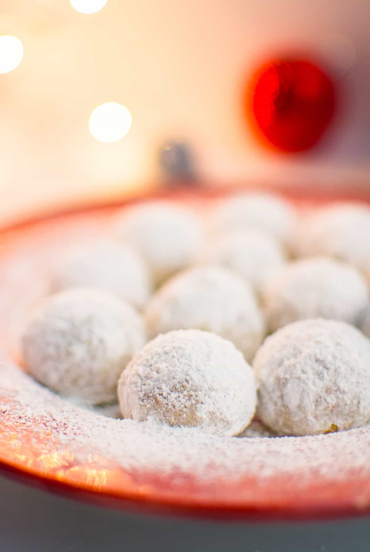 A plate of vegan snowball cookies dusted with powdered sugar. 