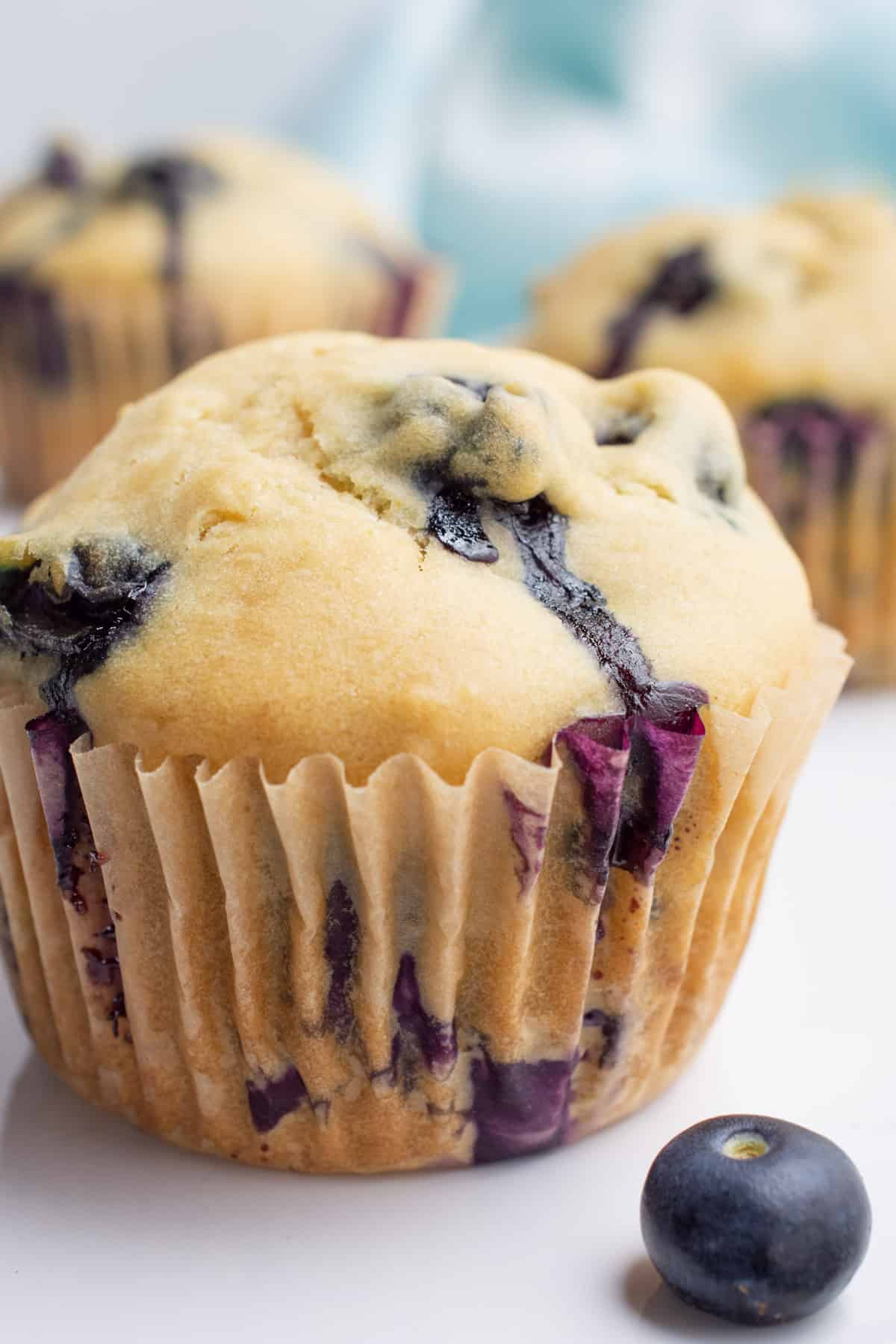 Close up of a vegan blueberry muffin in a tan muffin paper.