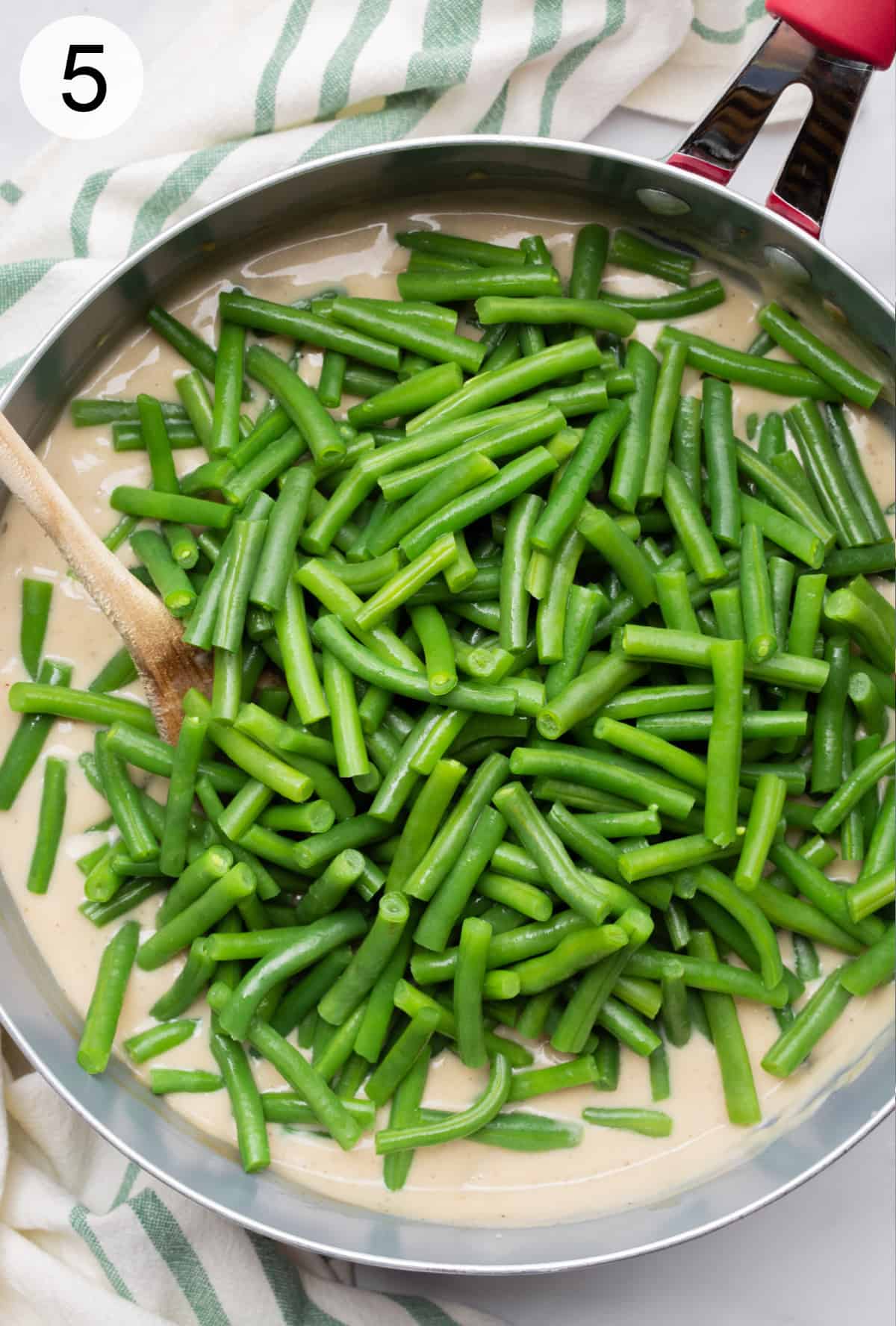 Green beans on top of mushroom gravy in a large pan.