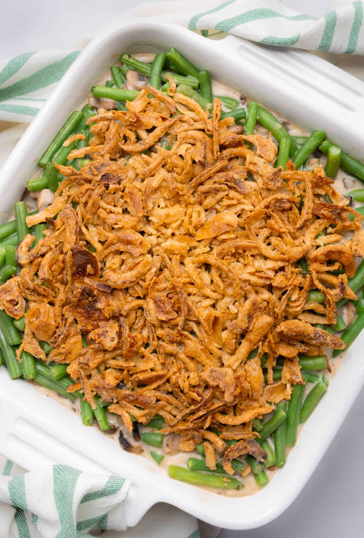 Vegan green bean casserole in a square white dish, after baking in the oven.