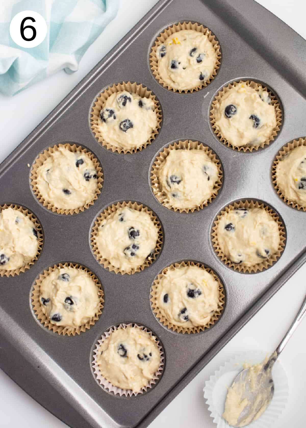 Blueberry muffin batter in a muffin tin.