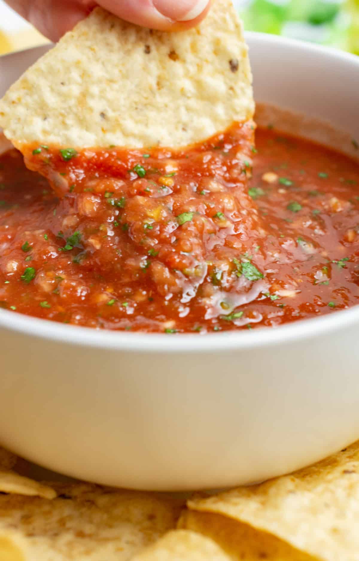 A tortilla chip being dipped into a bowl of salsa.