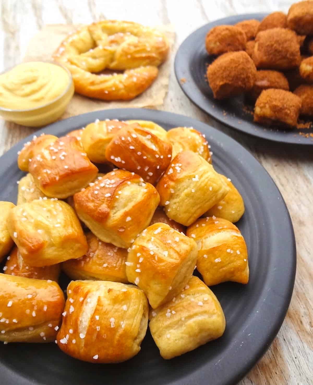 Homemade vegan pretzel bites topped with coarse sea salt on a black plate.