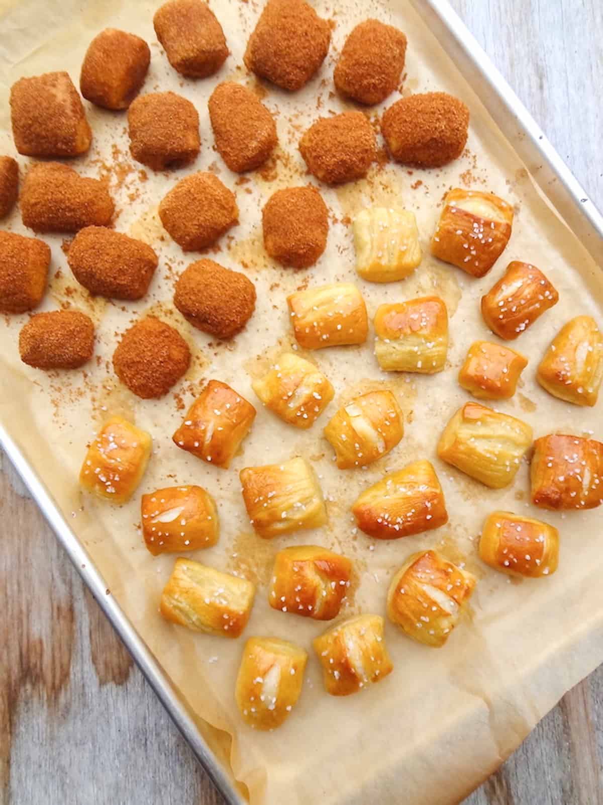 A baking sheet with vegan soft pretzel bites, half covered in cinnamon and sugar and the other half topped with coarse sea salt.