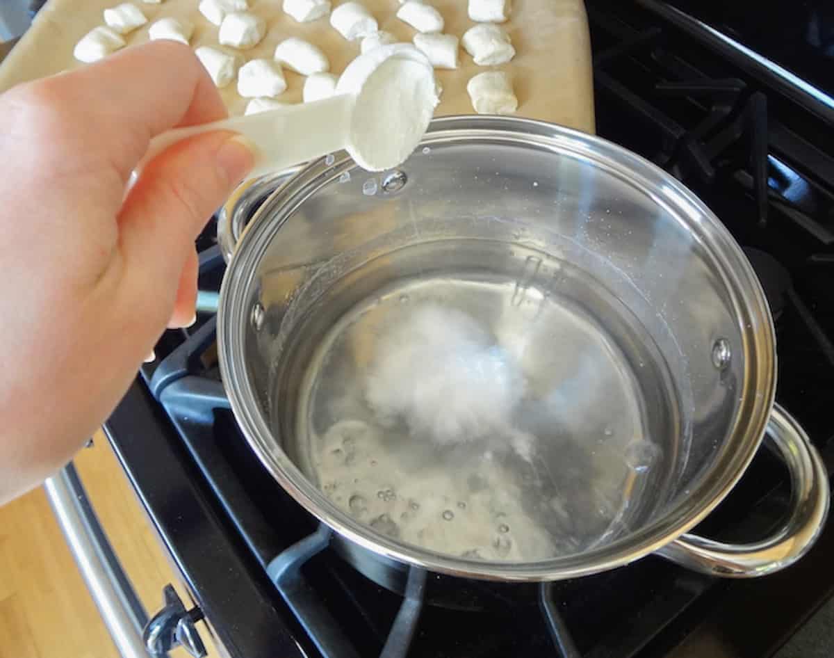 Baking soda being added to a pot of hot water.
