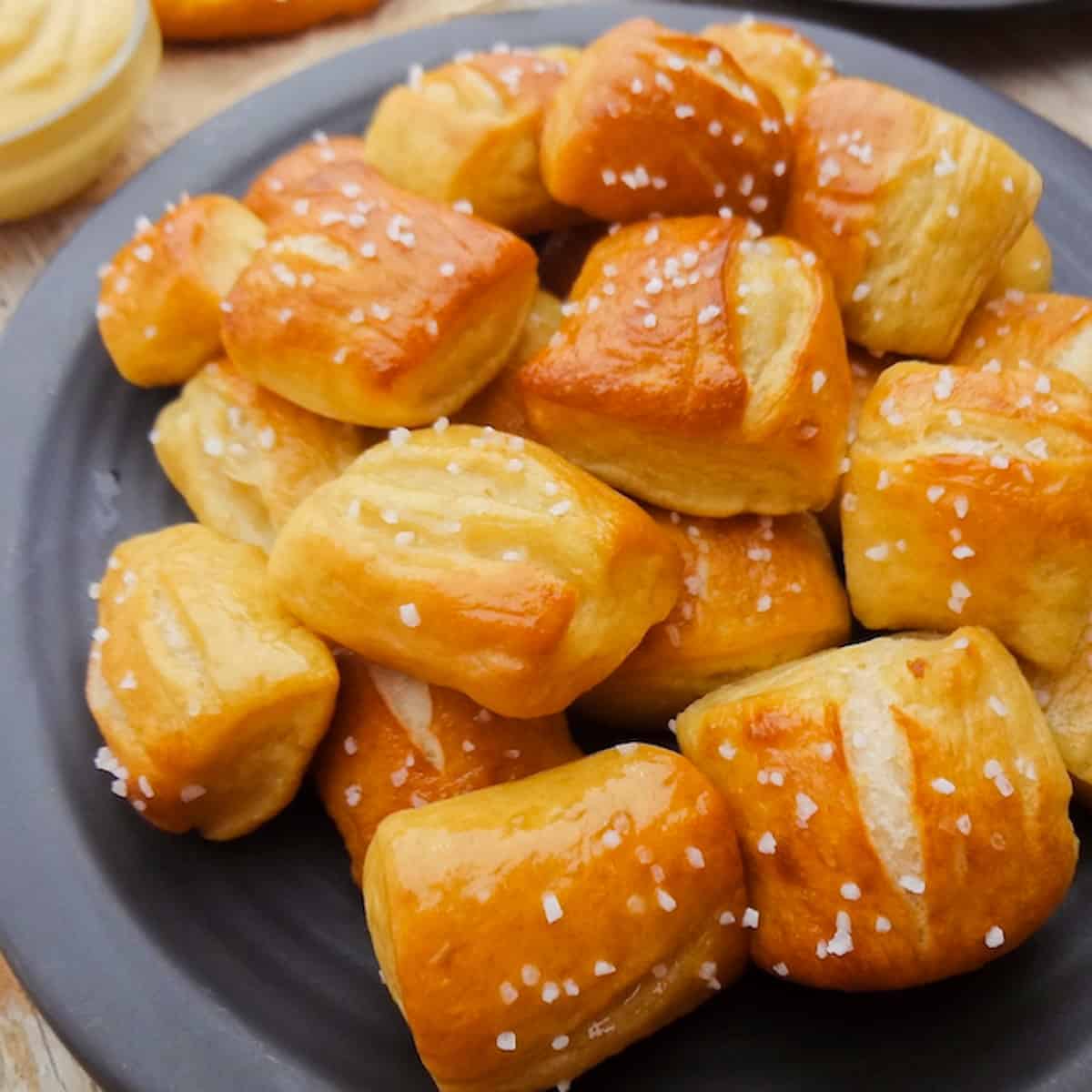 A pile of soft pretzel bites on a black plate.