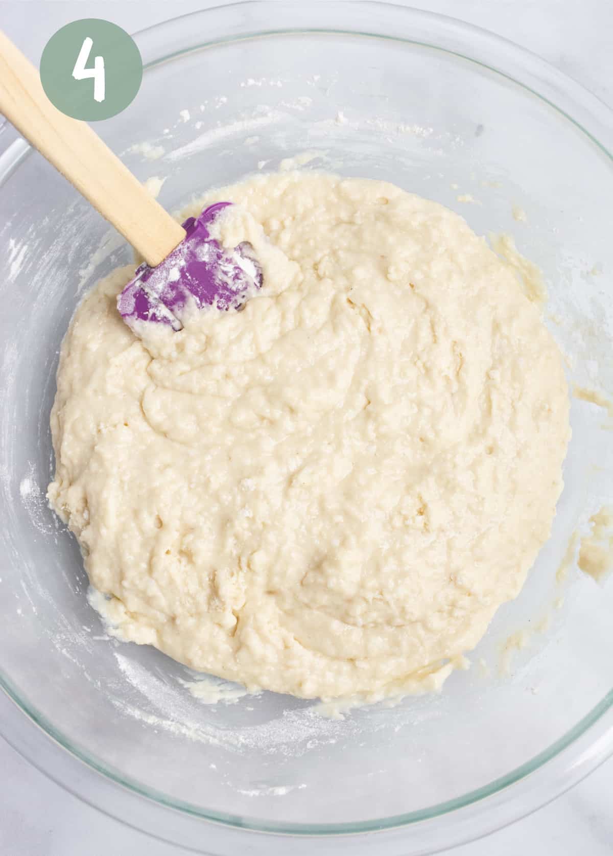 Batter mixed with a purple rubber spatula in a glass bowl.