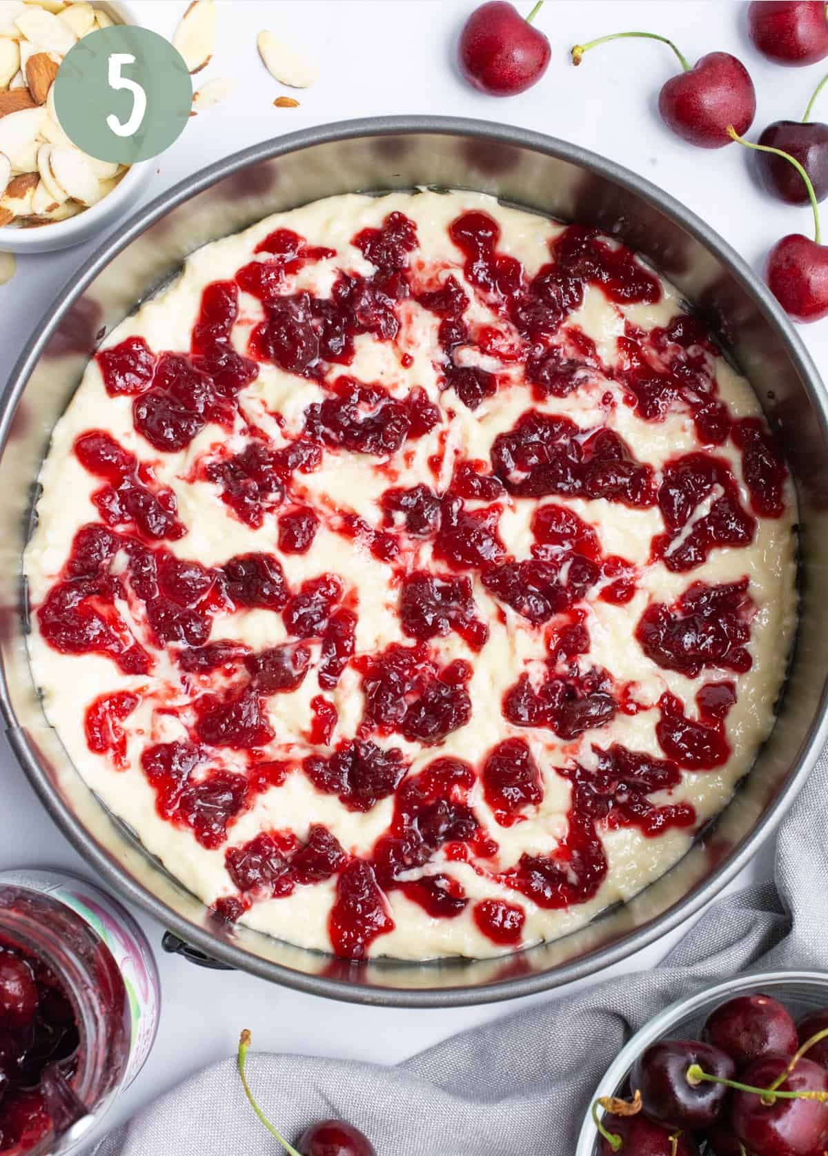 Cherry preserves dolloped onto batter in a spring from pan.