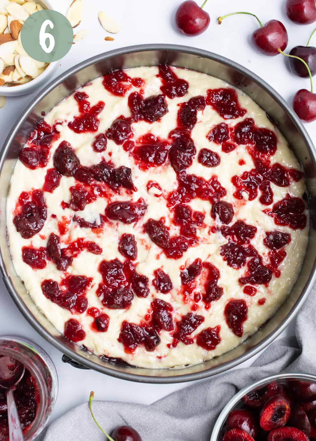 A second layer of cherry preserves dolloped onto batter in a spring from pan.