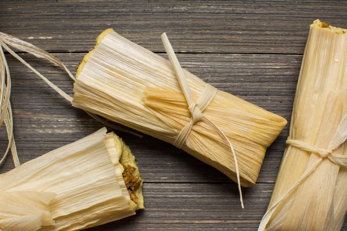 3 vegan tamales wrapped in corn husks and tied with a corn husk strip.