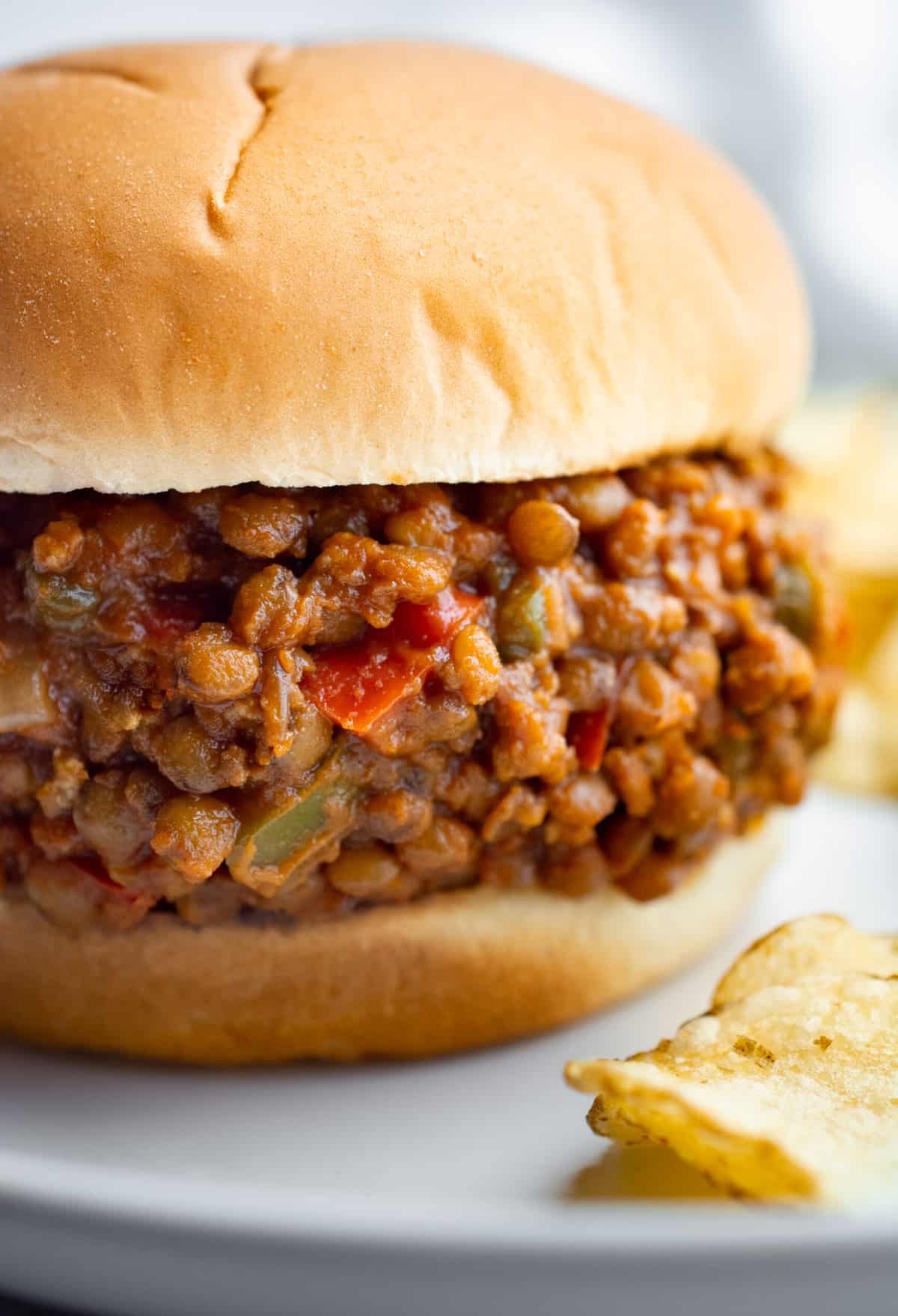 Lentil sloppy joes with red bell peppers, tofu, and jalapeño on a white bun.