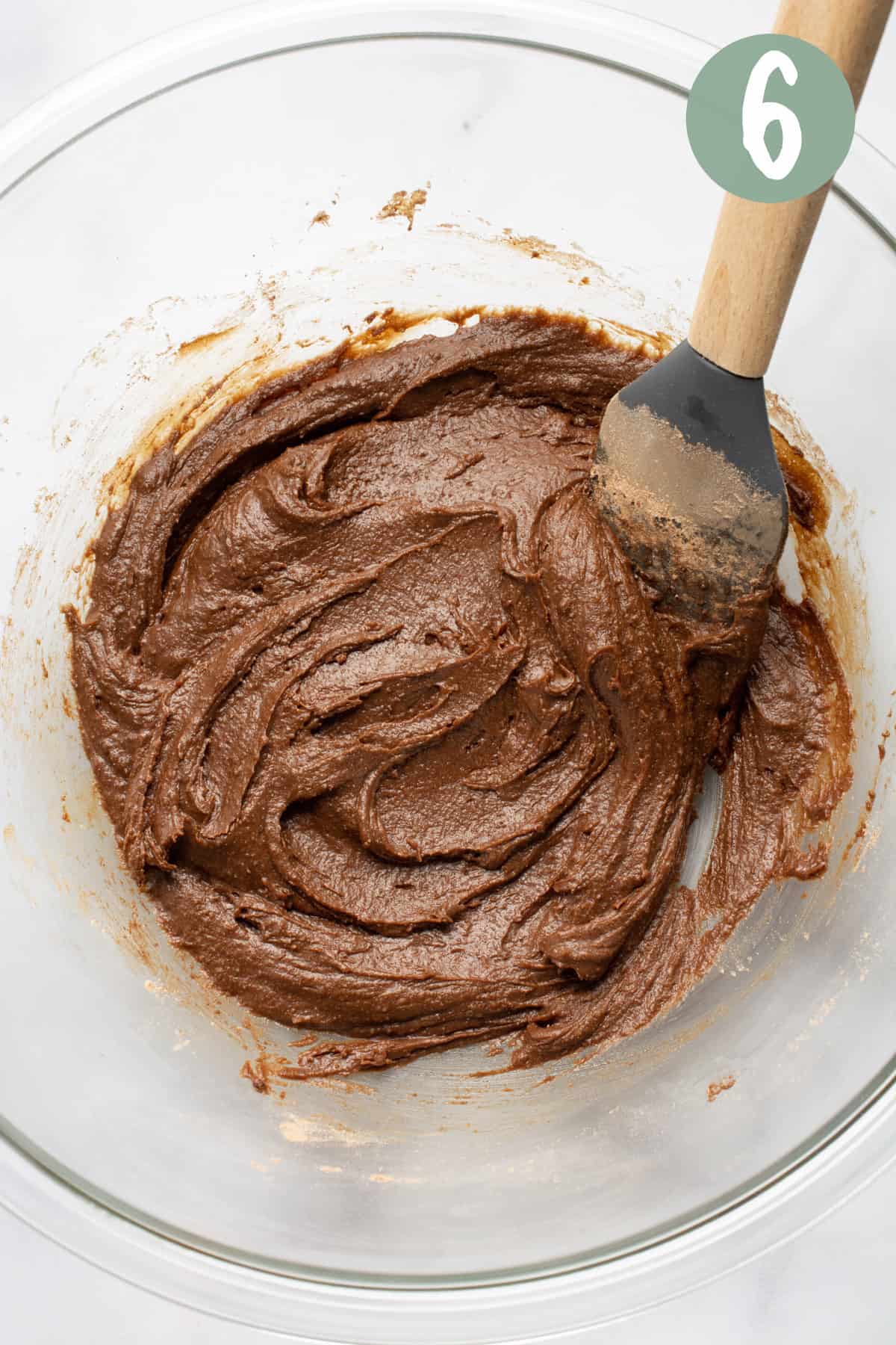 Vegan brownie batter in a glass bowl with a silicone spatula.