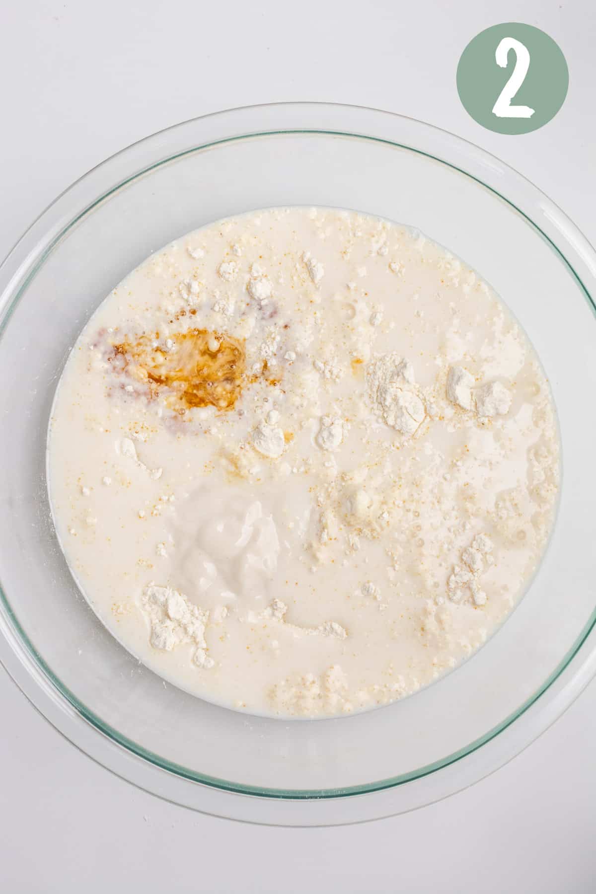A glass bowl of dry ingredients with wet ingredients poured in.