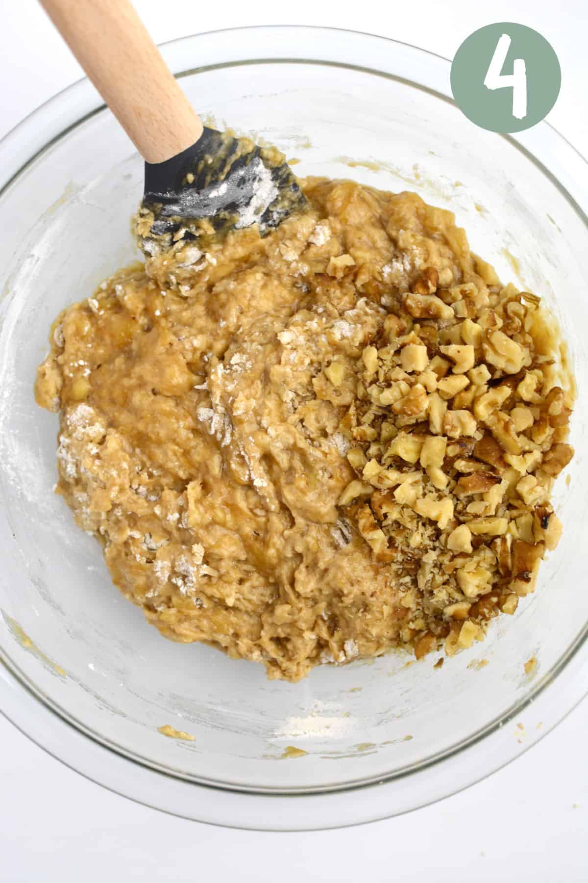 Vegan banana bread batter with walnuts on top in a glass bowl.