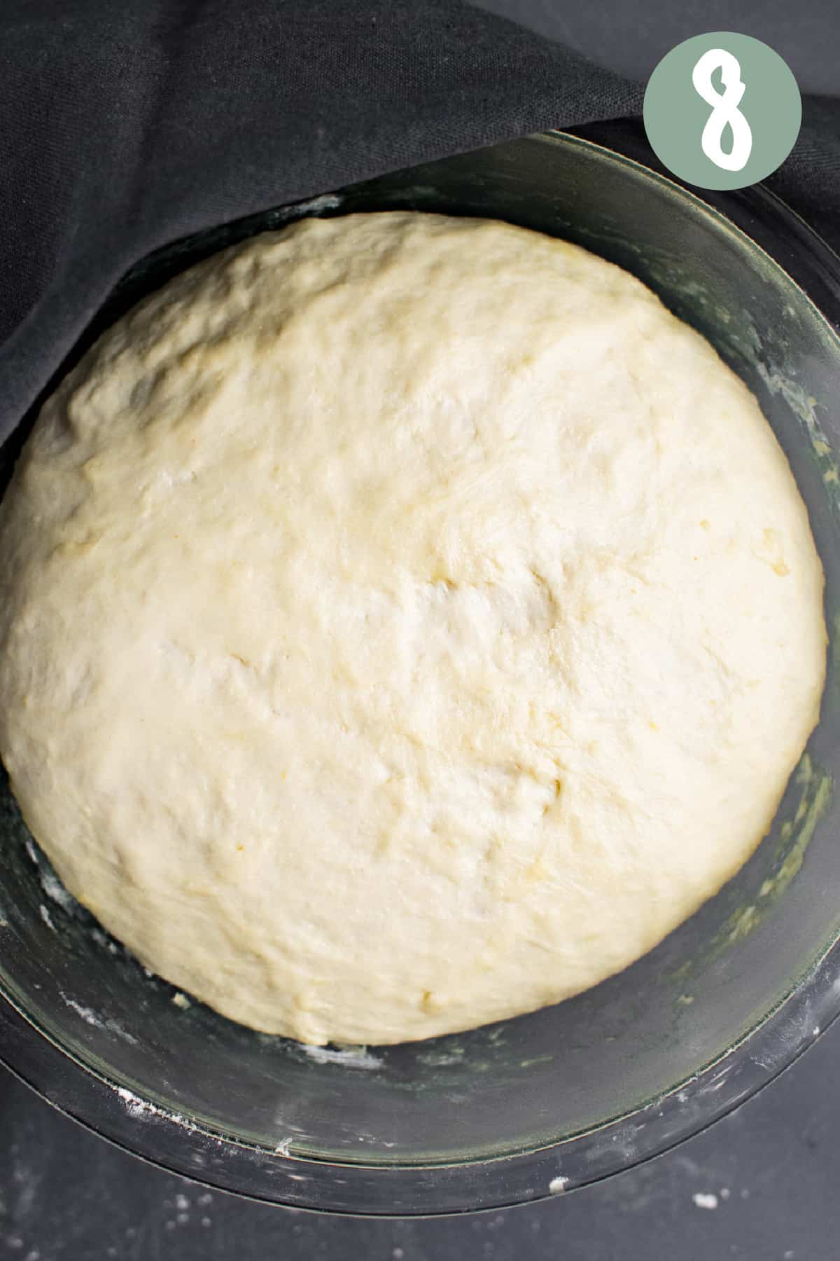 Risen dough ball in a glass bowl.