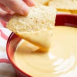 A tortilla chip dipped in cheese sauce.