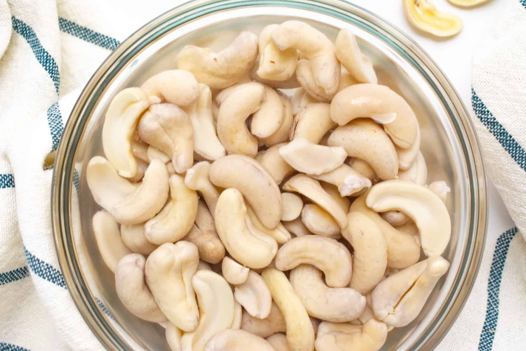 Raw cashews in a glass bowl soaking in room temperature water.