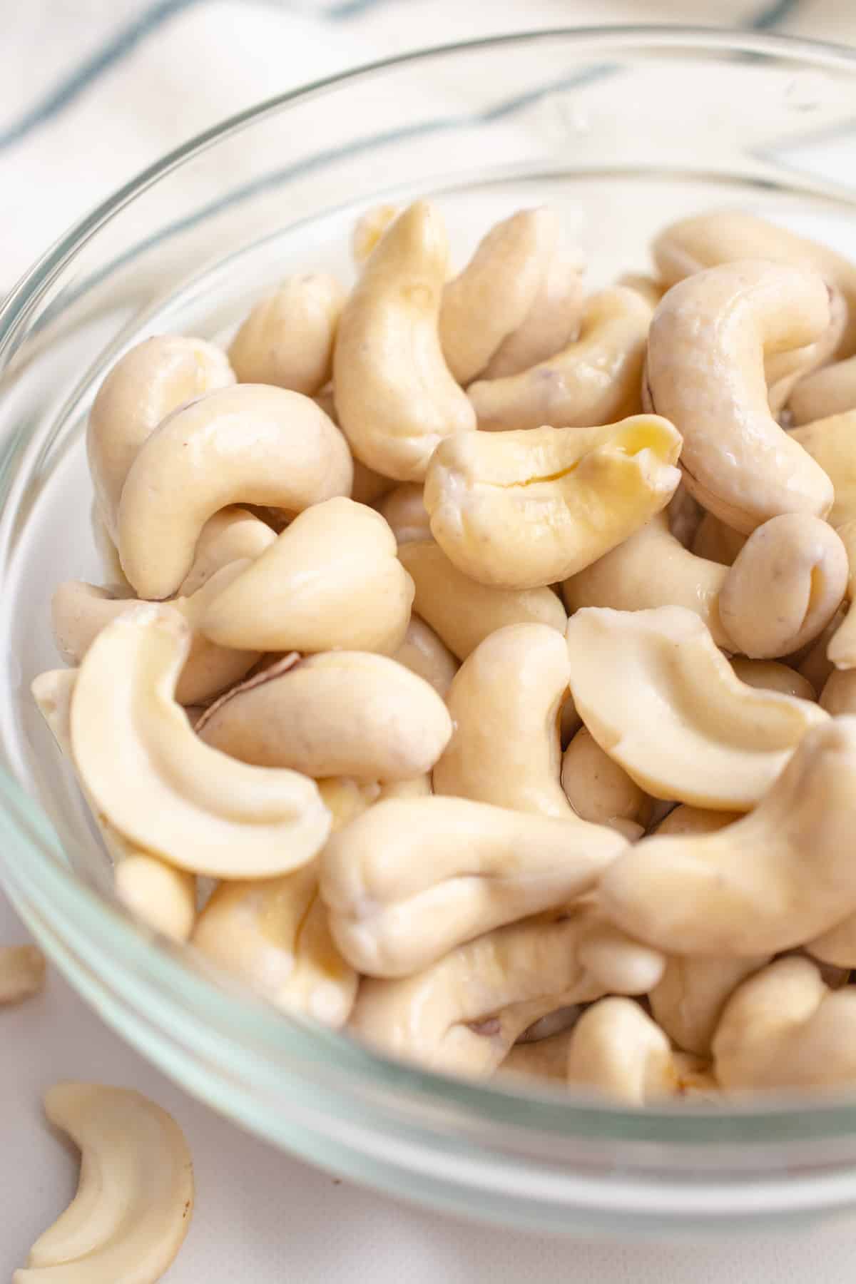 Softened cashews in a glass bowl after soaking.