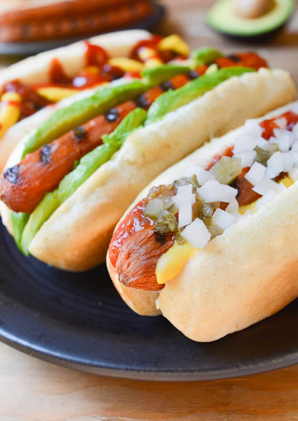 Three carrot hotdogs in buns with toppings.