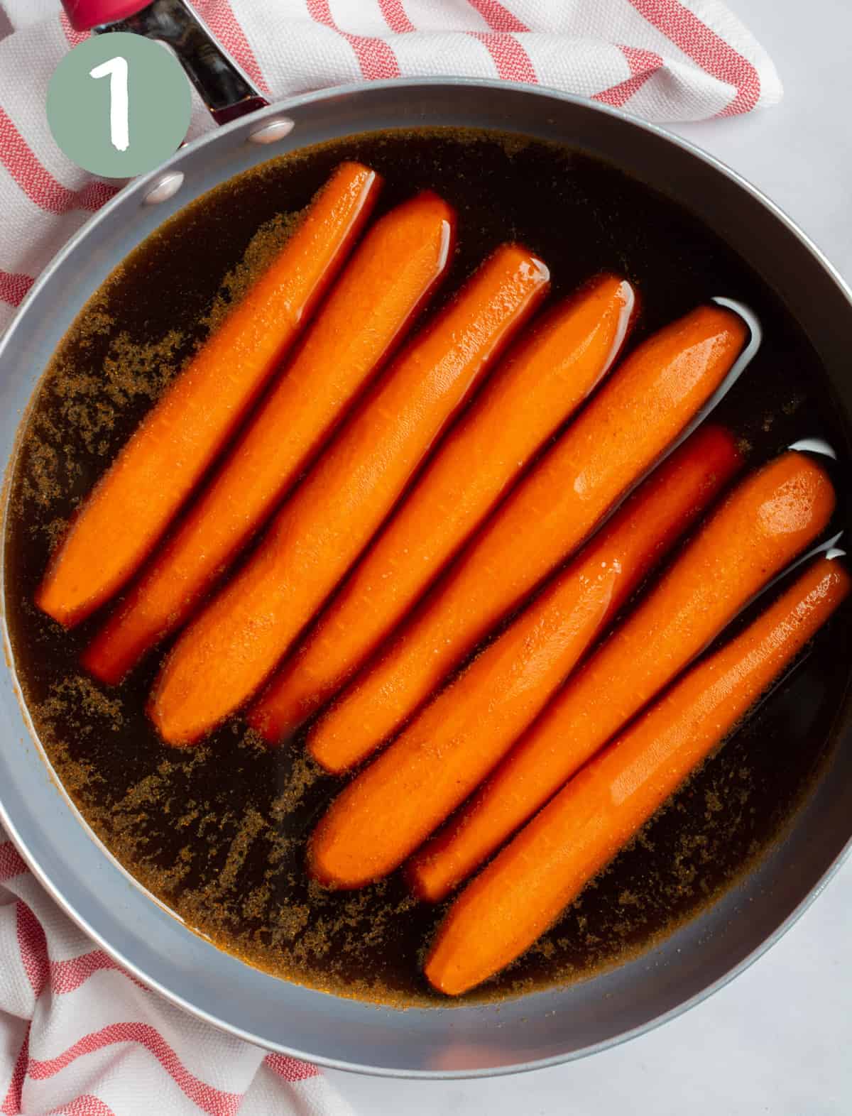 Carrots shaped into a hot dog in a pan with marinade.