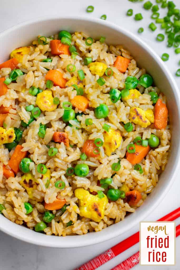 Vegan fried rice with tofu, carrots and peas in a white bowl.