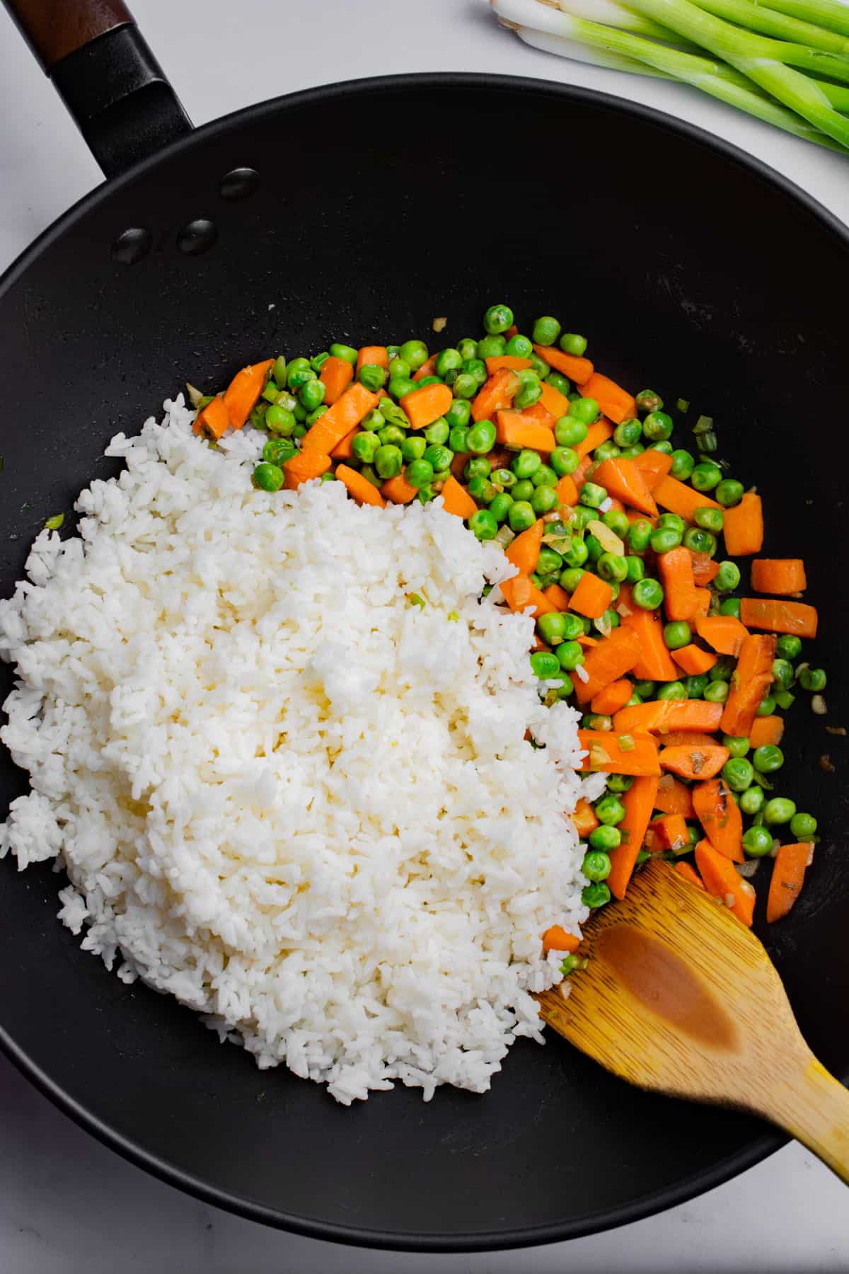 White rice, peas and carrots in a wok.