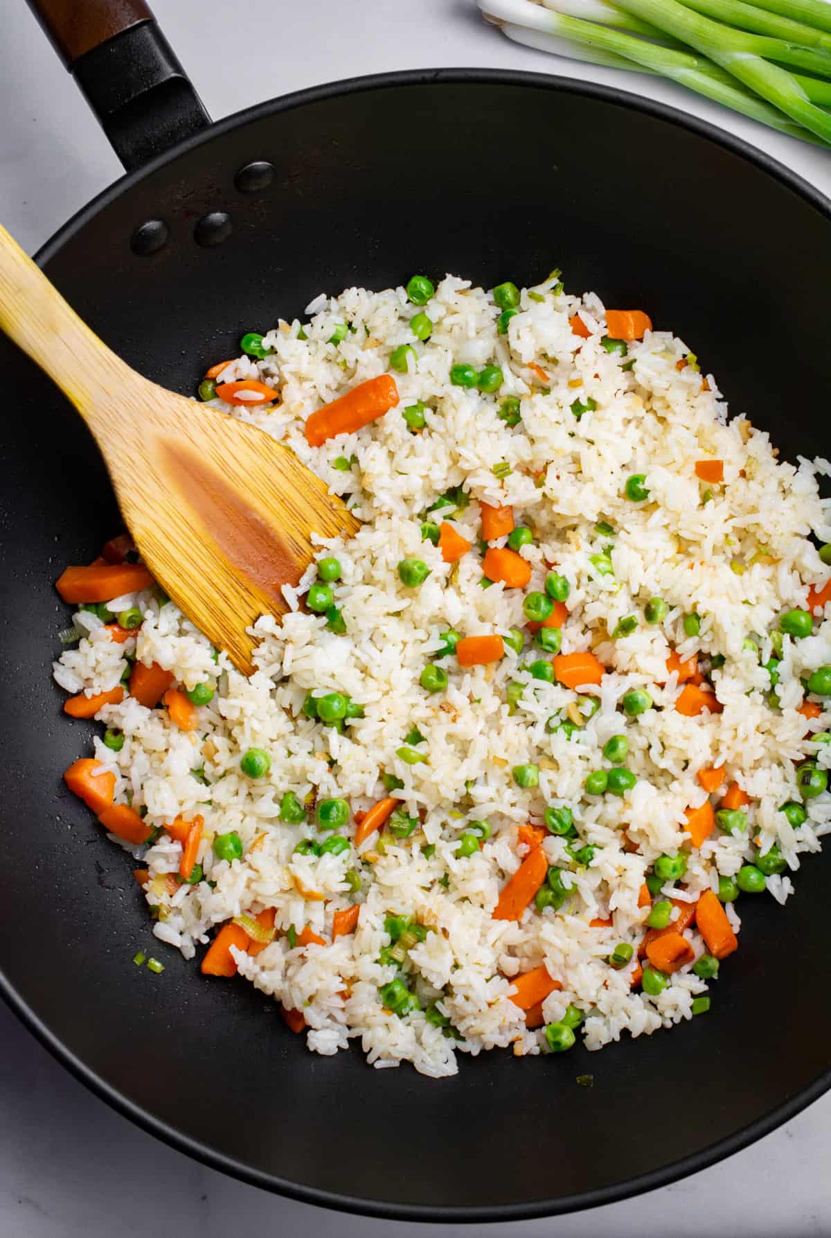White rice, peas and carrots mixed in a wok.