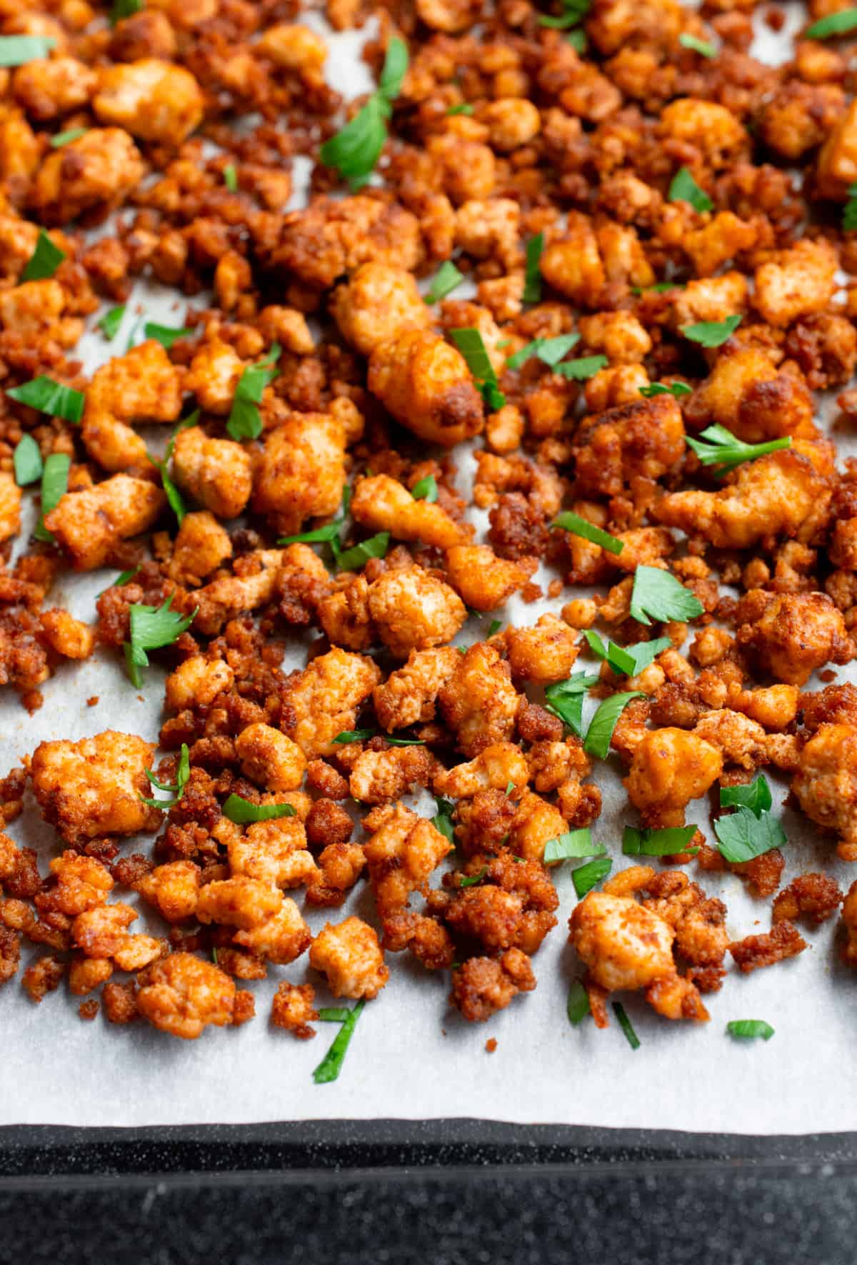 Tofu ground beef on a baking sheet topped with freshly chopped parsley.