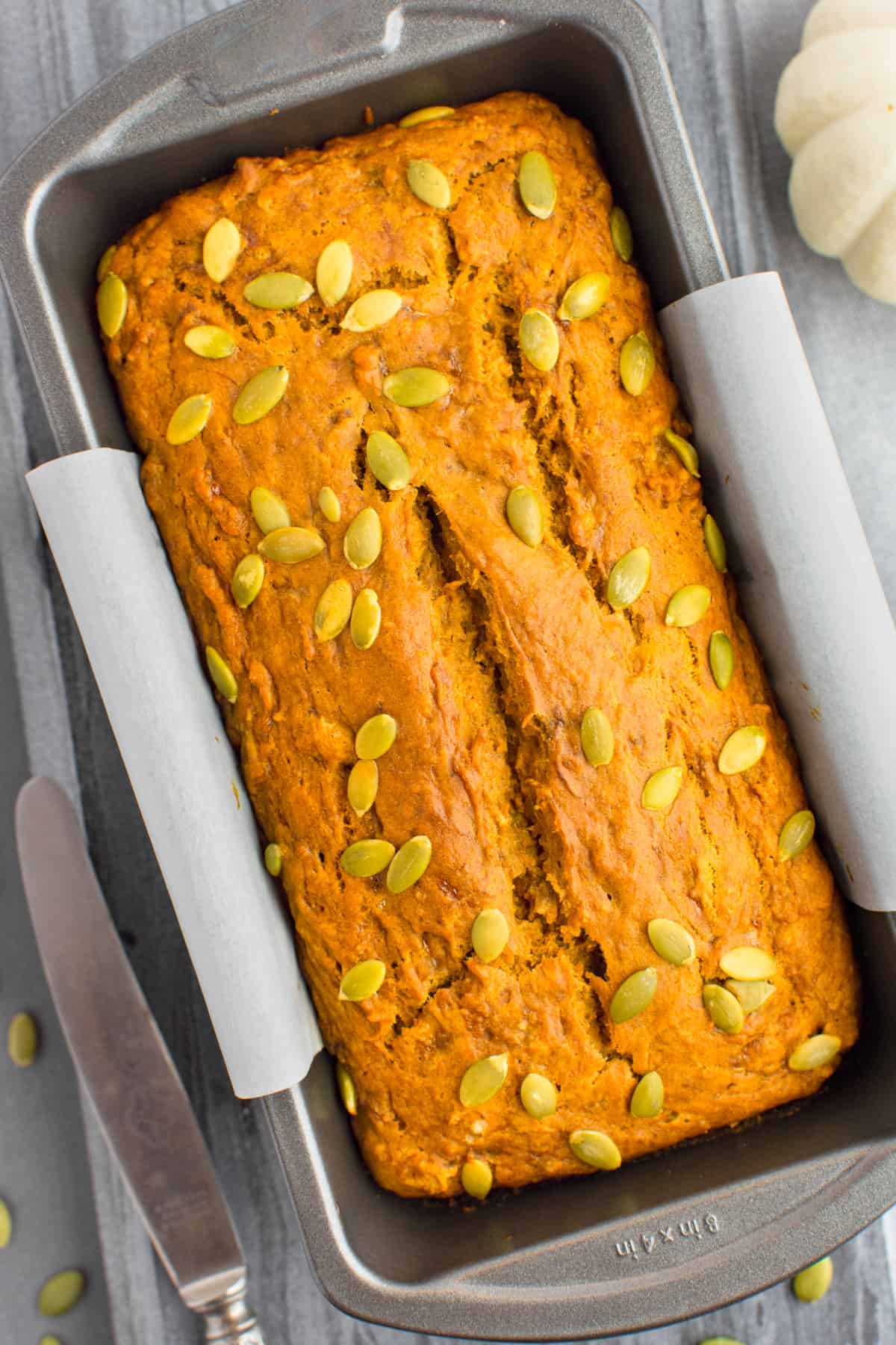 Vegan pumpkin banana bread topped with pumpkin seeds in a loaf pan.