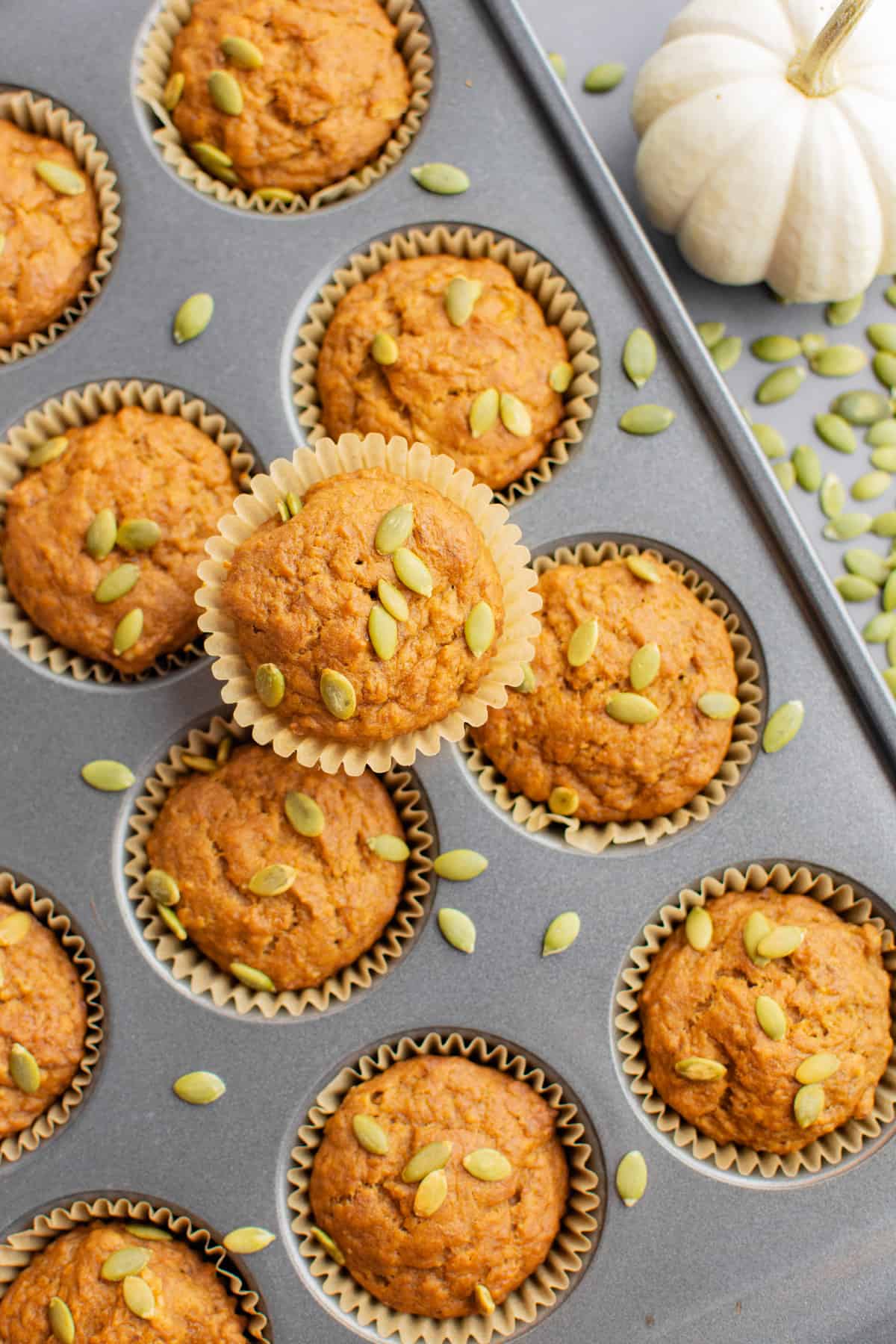 Pumpkin banana muffins topped with pepitas in a muffin pan.