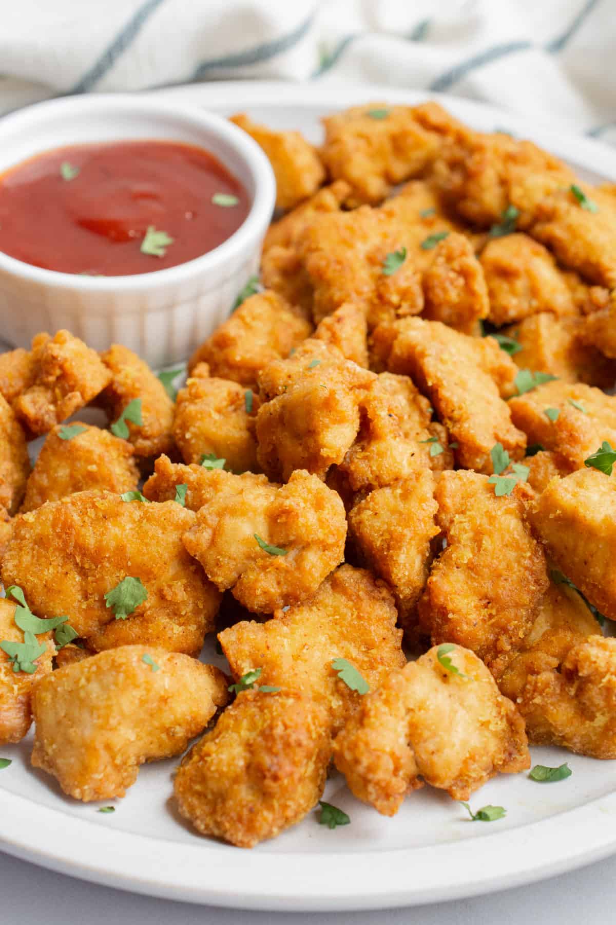 Tofu chicken nuggets on a plate with BBQ sauce for dipping.